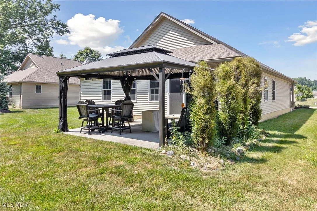 Rear view of house featuring a gazebo, a patio area, a yard, and roof with shingles