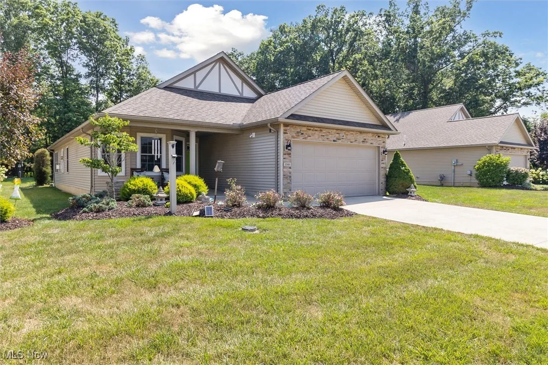 View of front facade with roof with shingles, an attached garage, a front lawn, and driveway
