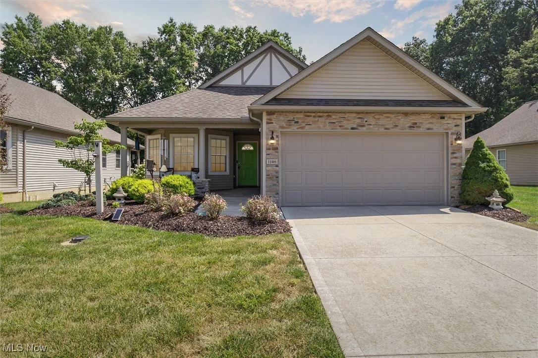 View of front of property featuring a front lawn, concrete driveway, an attached garage, and covered porch