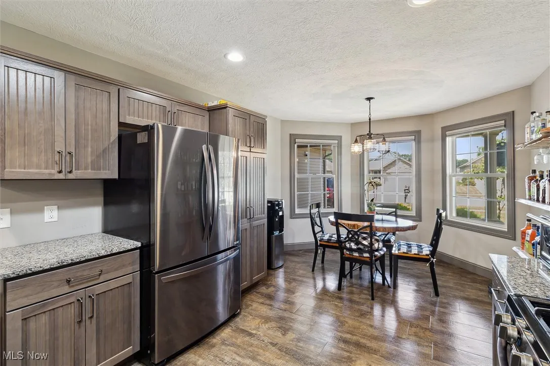 Kitchen with appliances with stainless steel finishes, dark wood-style flooring, a textured ceiling, recessed lighting, and a chandelier