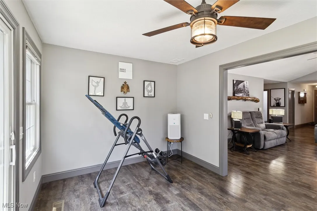 Exercise room featuring wood finished floors, healthy amount of natural light, and a ceiling fan