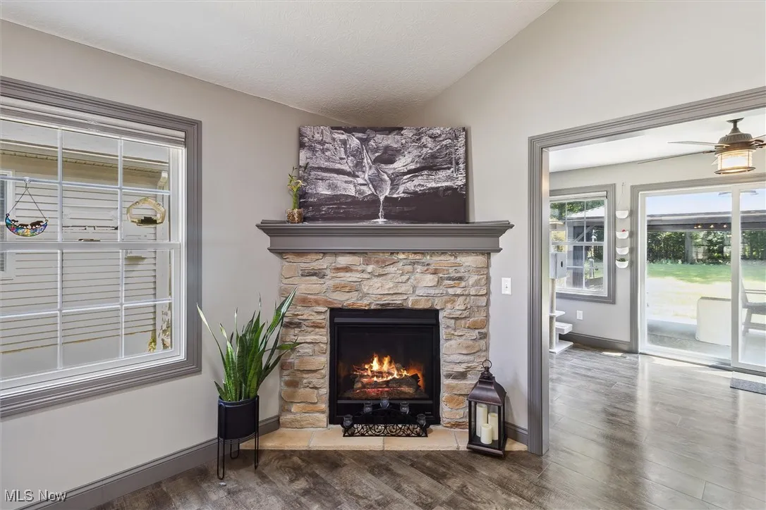 Living area with lofted ceiling, wood finished floors, a fireplace, and a ceiling fan