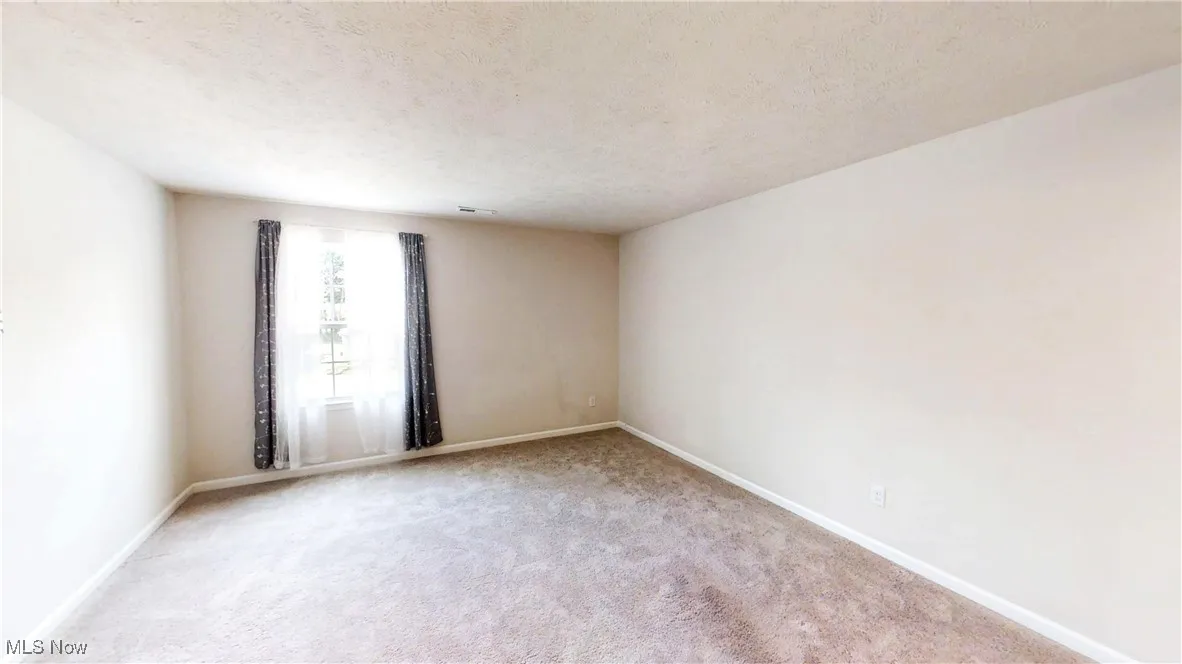 Carpeted spare room with baseboards