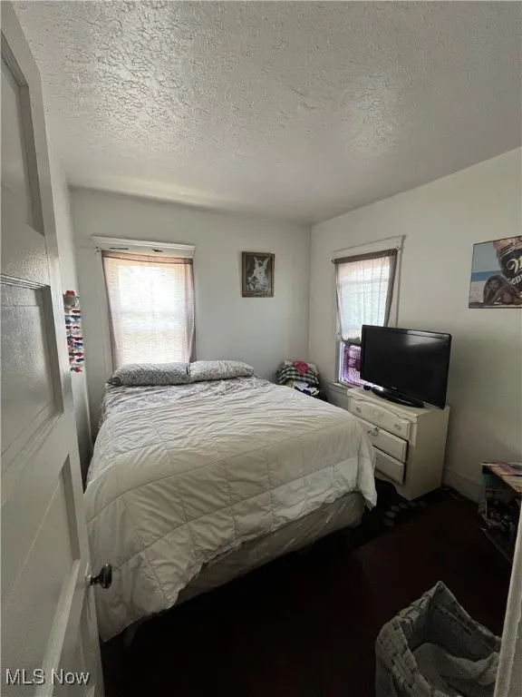 Bedroom with multiple windows, a textured ceiling, and wood finished floors