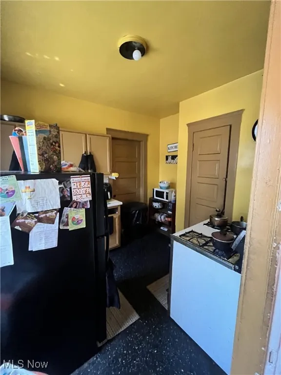 Kitchen featuring freestanding refrigerator and white microwave