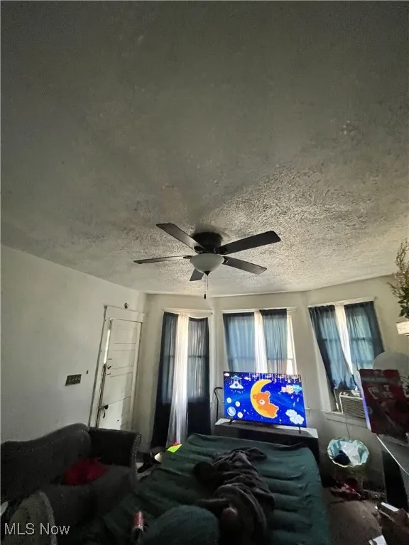 Bedroom with a textured ceiling and a ceiling fan