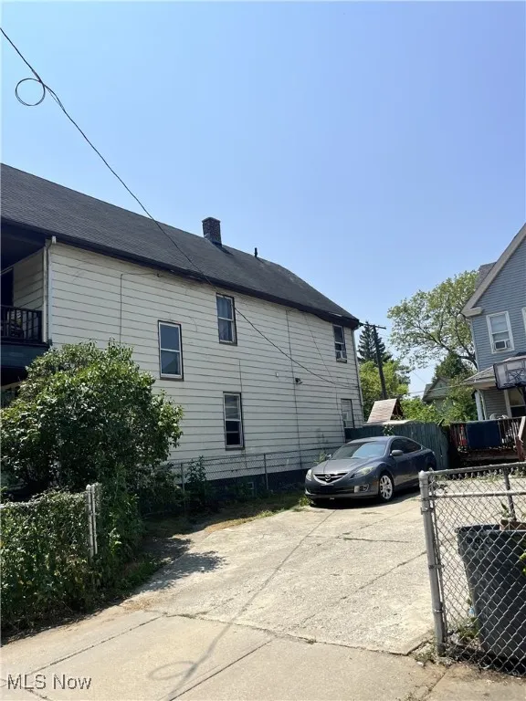 View of property exterior featuring a chimney and concrete driveway