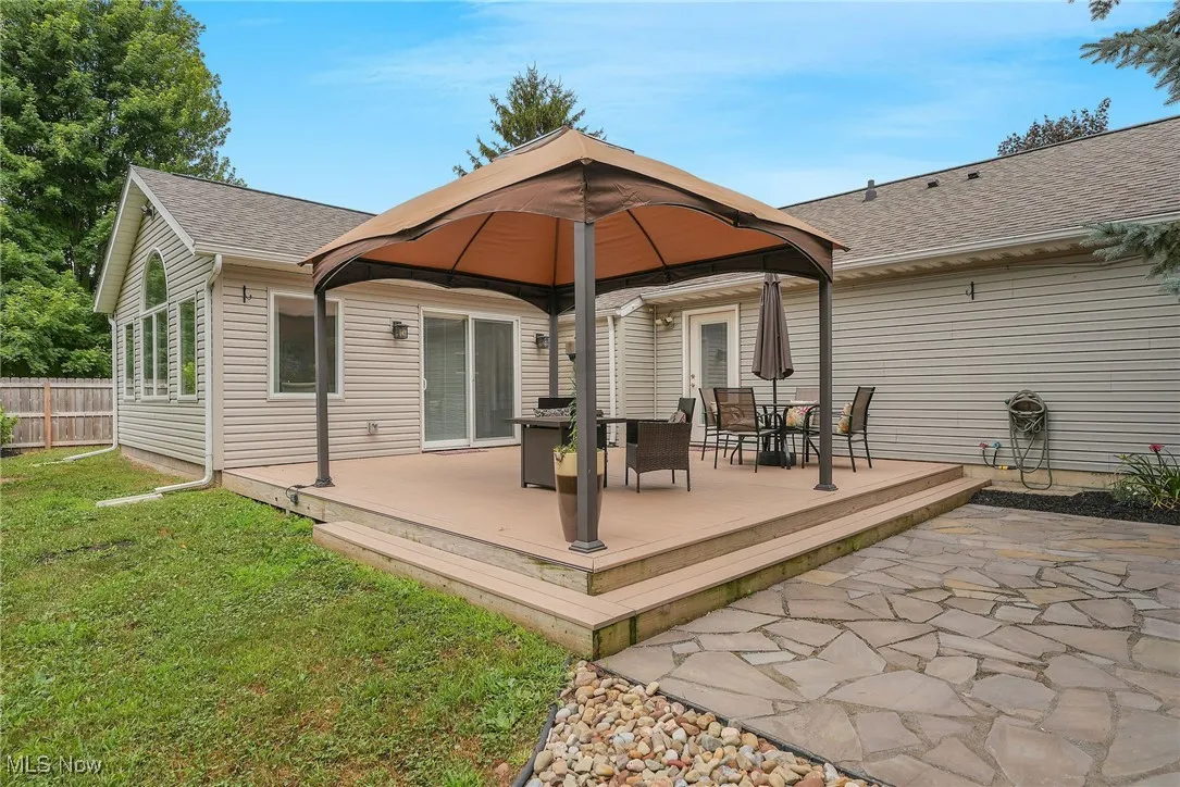Back of house featuring a gazebo, a shingled roof, a deck, and outdoor dining space