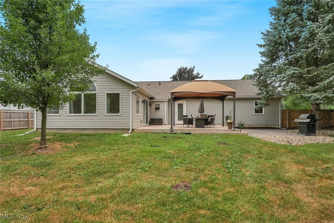Back of property with a gazebo, a fenced backyard, a deck, and roof with shingles