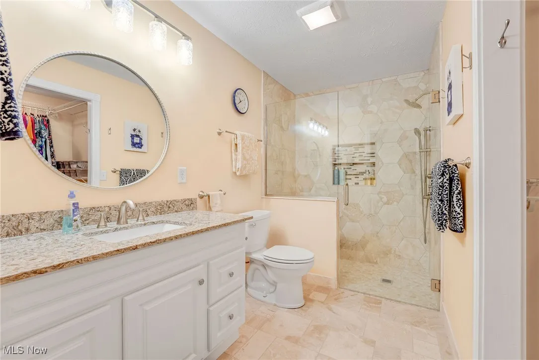 Full bath featuring vanity, ceramic floor a walk in shower, and a spacious closet