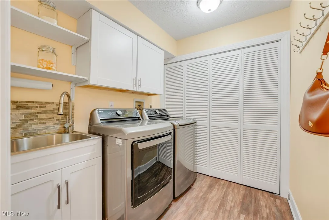 Laundry room featuring cabinet space, washing machine and dryer, and light wood finished floors