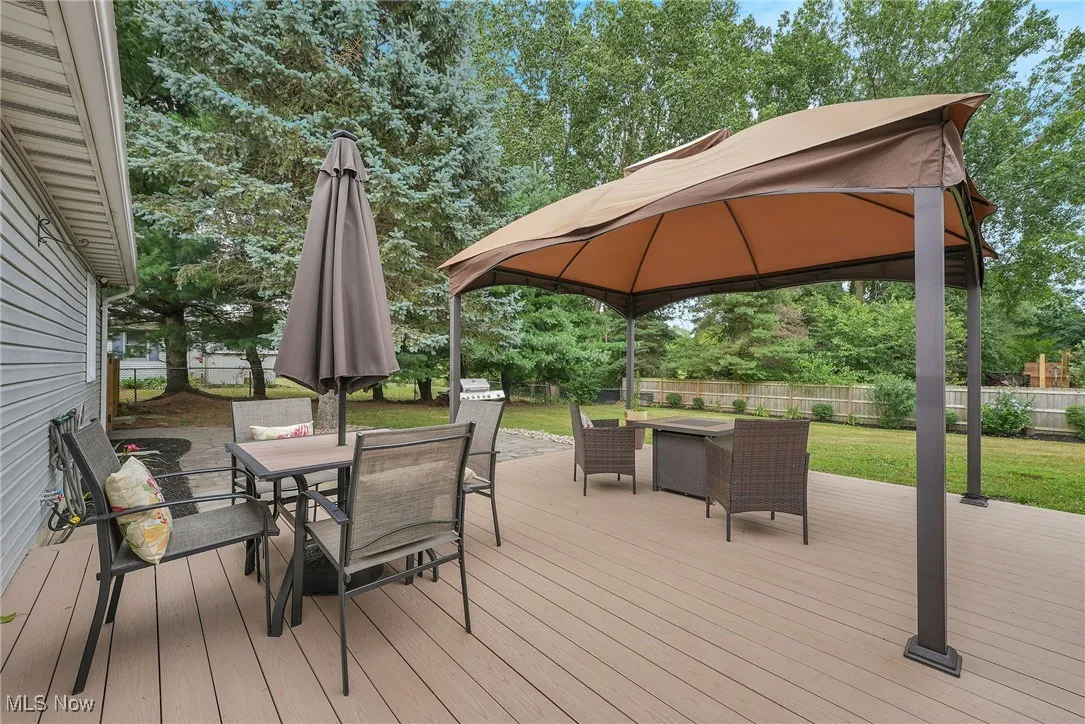 Deck featuring outdoor dining space, a gazebo, and flagstone patio with a fenced backyard.
