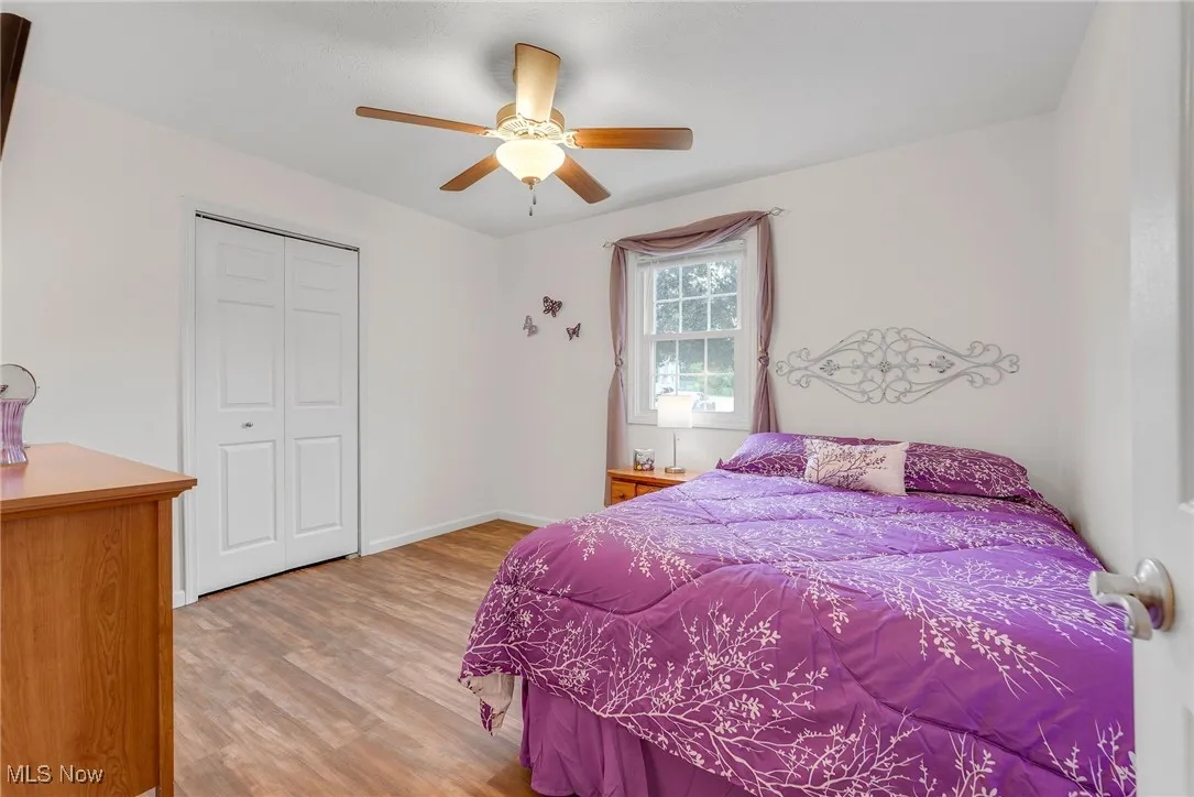 Bedroom with light luxury vinyl floors a closet, and a ceiling fan