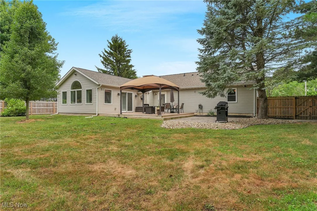 Back of house featuring a fenced backyard, a gazebo, a patio, and a shingled roof