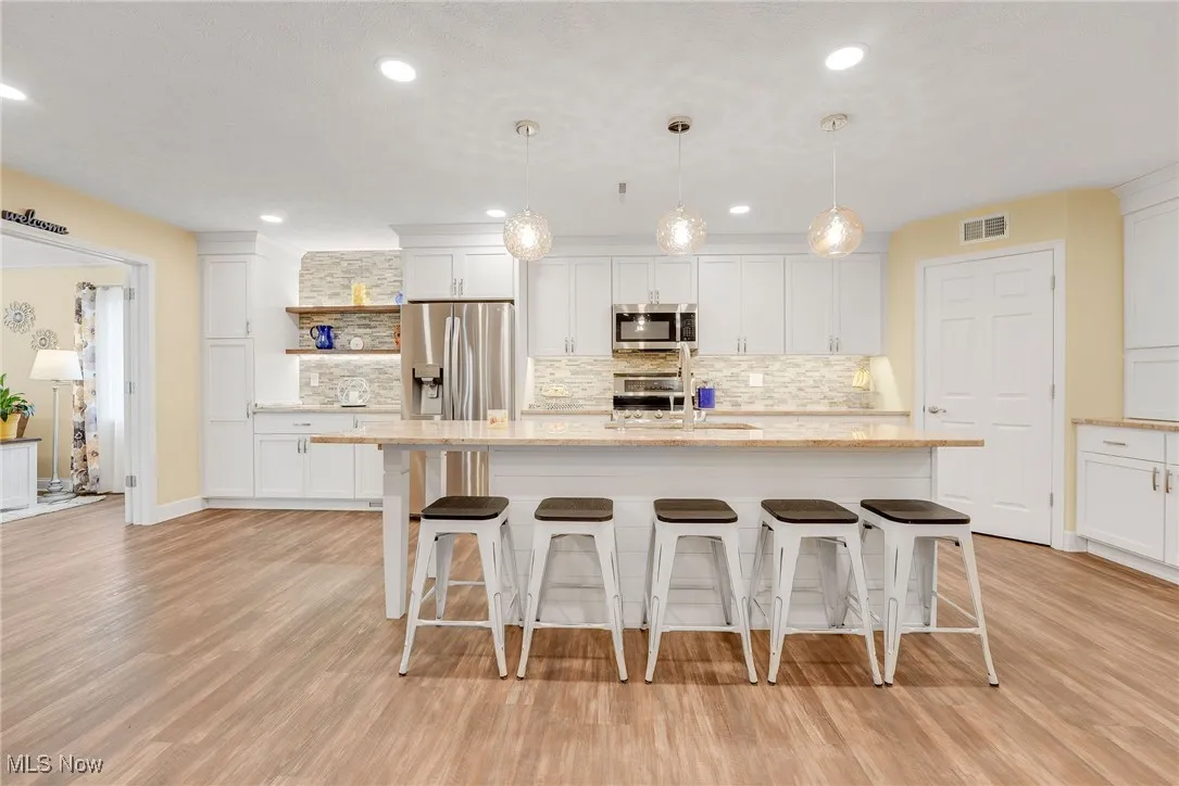 Kitchen with open shelves, recessed led lighting, decorative backsplash, stainless steel appliances, and luxury vinyl flooring