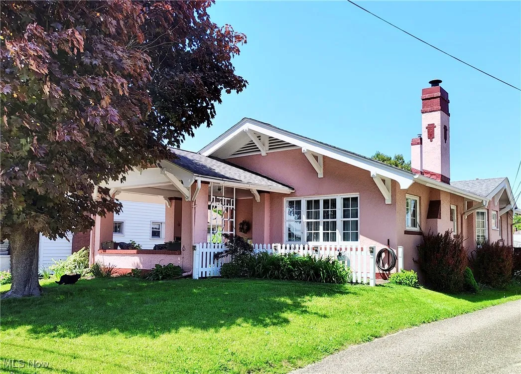Bungalow with a chimney, a front lawn, stucco siding, and a porch