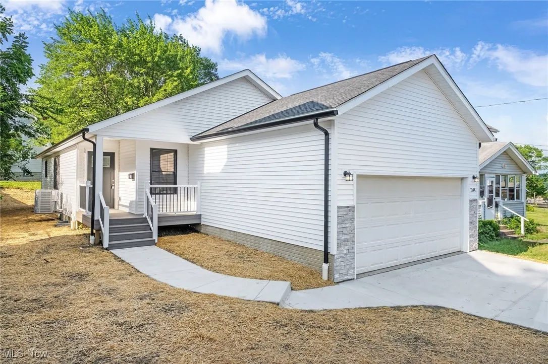 Ranch-style home with a porch, an attached garage, roof with shingles, and driveway