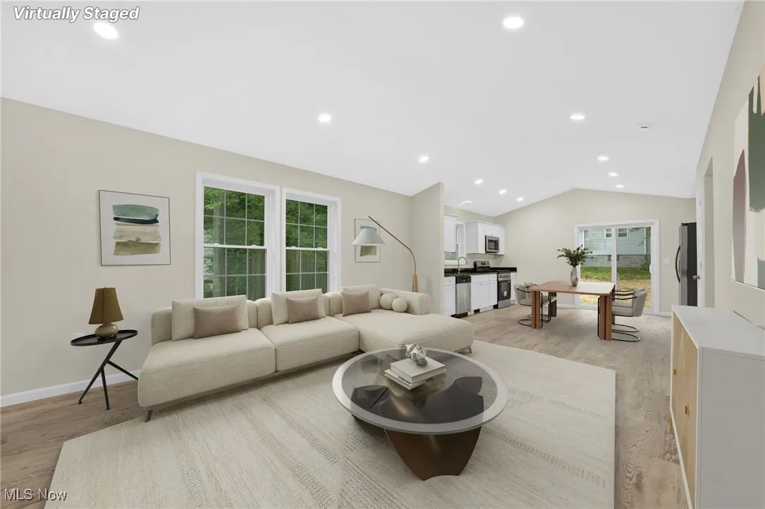 Living room featuring light wood-type flooring, healthy amount of natural light, vaulted ceiling, and recessed lighting