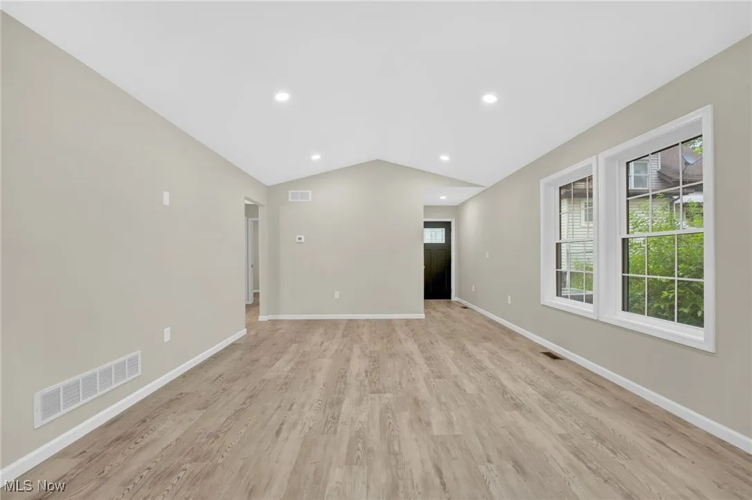 Unfurnished room featuring vaulted ceiling, light wood finished floors, and recessed lighting