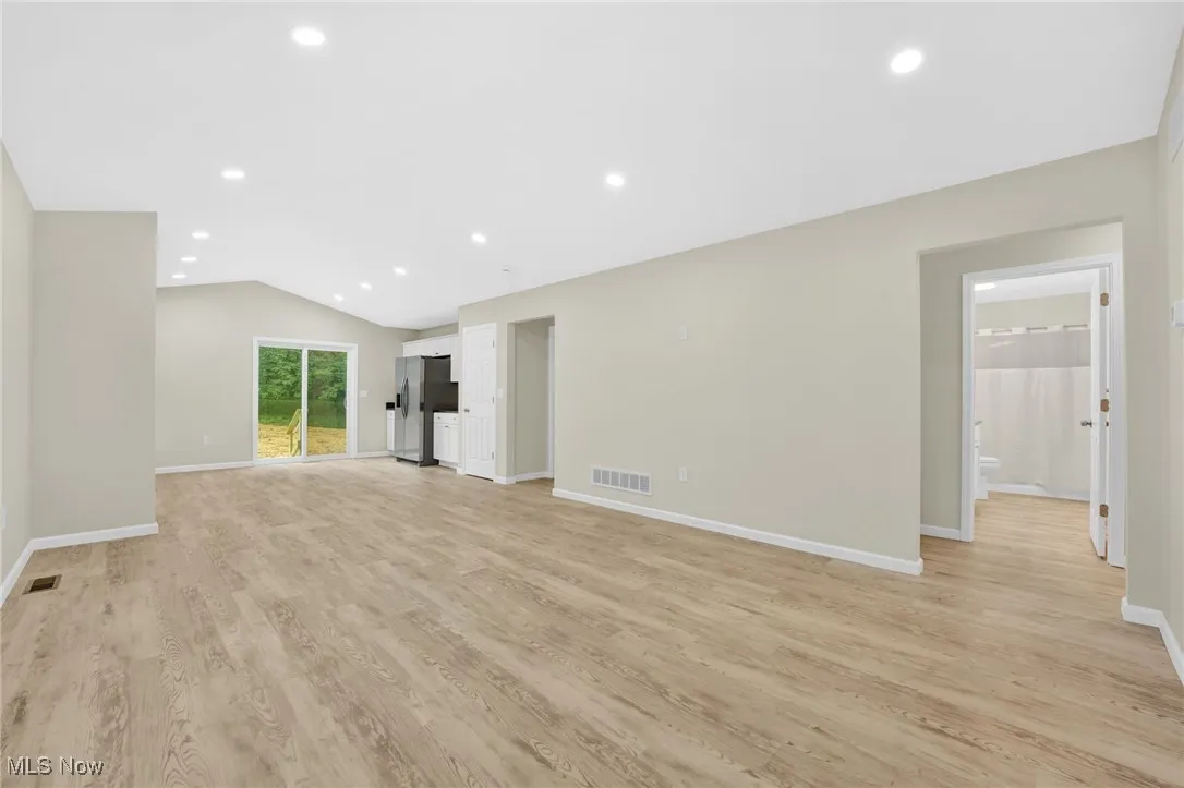 Unfurnished living room with light wood-style floors, vaulted ceiling, and recessed lighting