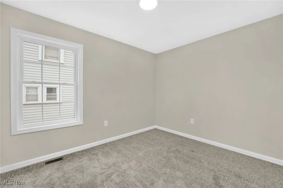 Carpeted spare room featuring baseboards
