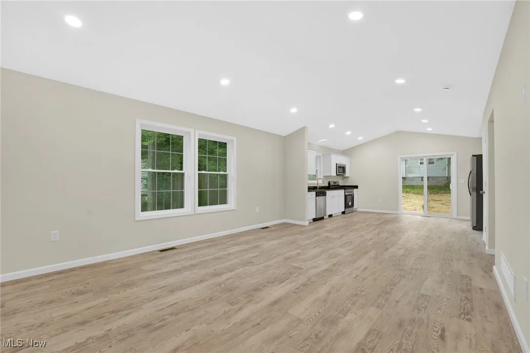 Unfurnished living room featuring lofted ceiling, light wood-style floors, and recessed lighting