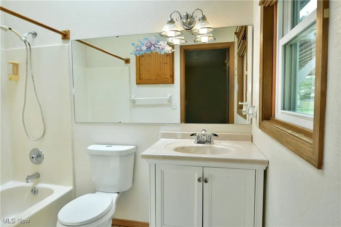 Full bath with vanity,  shower combination, plenty of natural light, and a chandelier