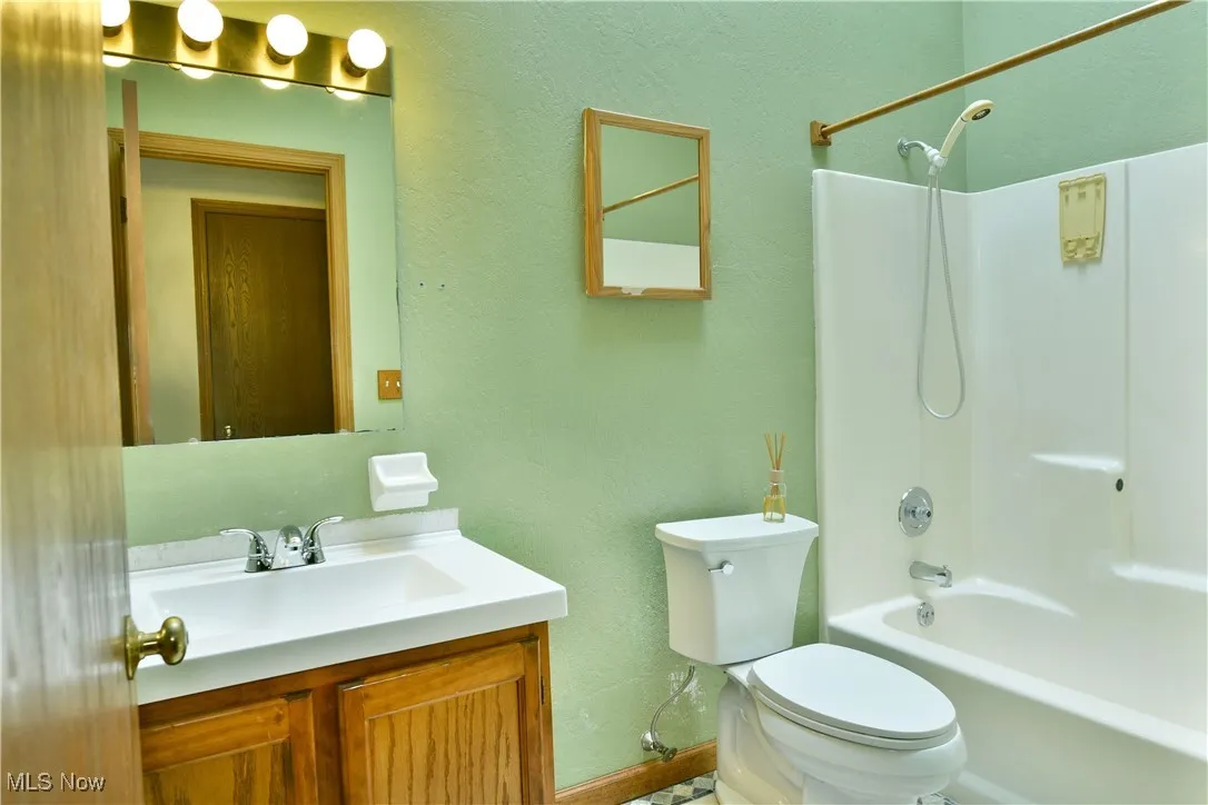 Bathroom with vanity, tub / shower combination, and a textured wall