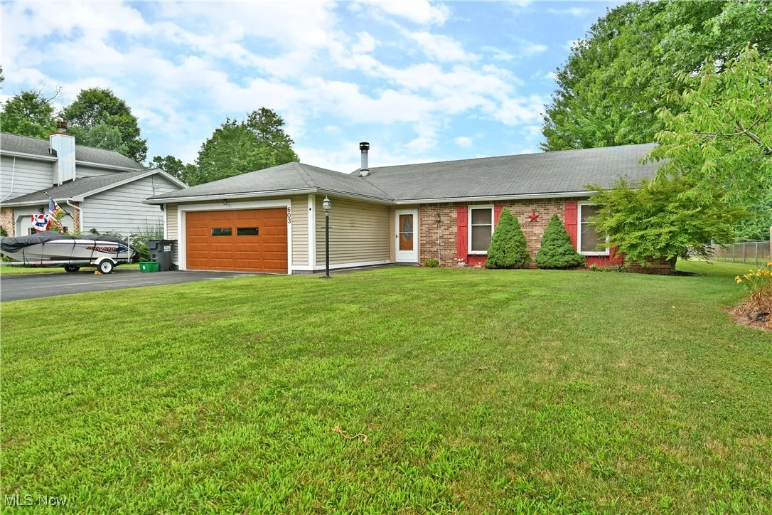 Ranch-style home with a garage, driveway, a front yard, and roof with shingles