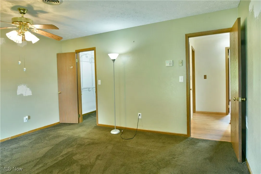 Unfurnished room featuring ceiling fan and carpet