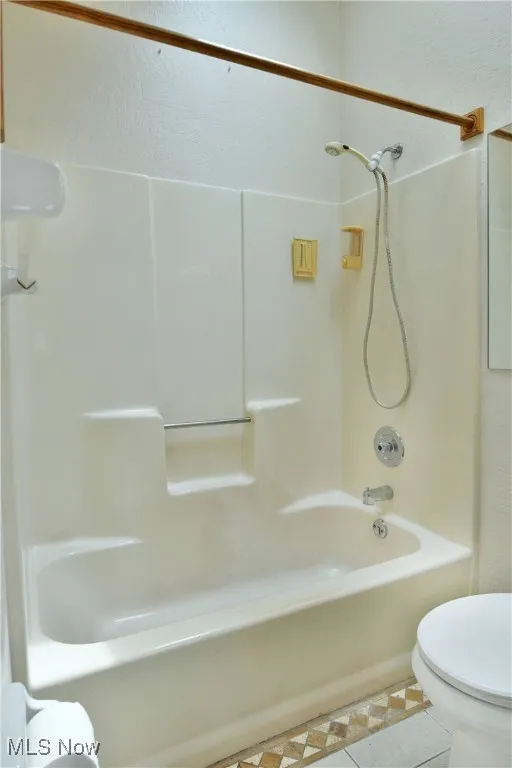 Full bath featuring washtub / shower combination and tile patterned flooring