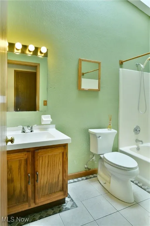 Bathroom with vanity, tub / shower combination, and tile patterned flooring