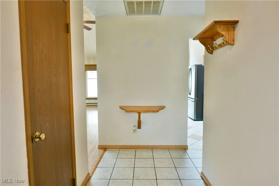 Hall featuring light tile patterned floors and baseboards