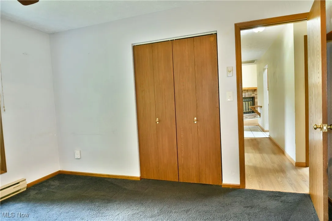 Unfurnished bedroom featuring carpet flooring, a closet, and a brick fireplace