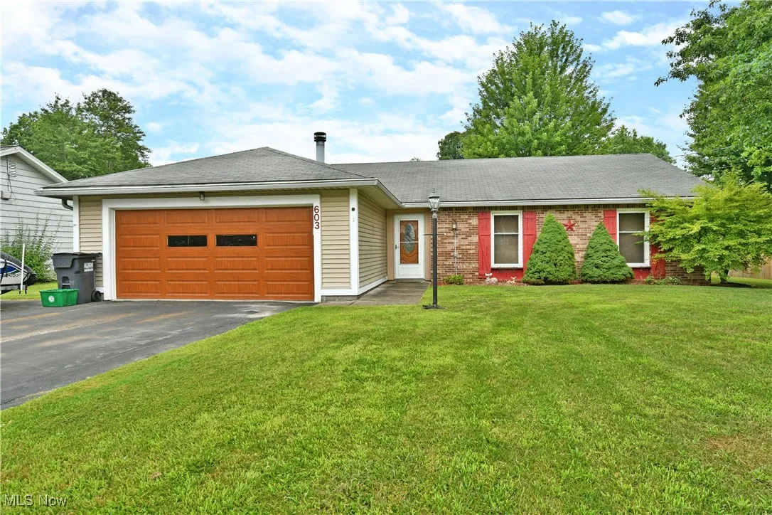 Single story home featuring a garage, asphalt driveway, a shingled roof, and a front lawn