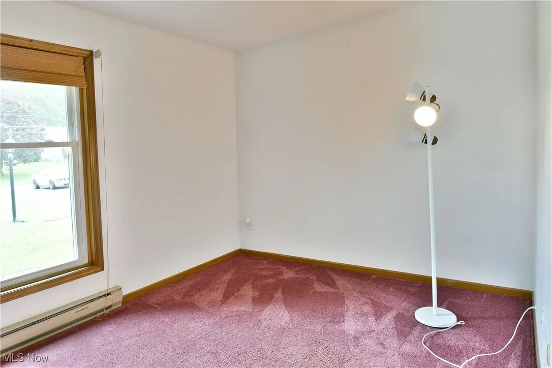 Carpeted empty room with baseboard heating and baseboards