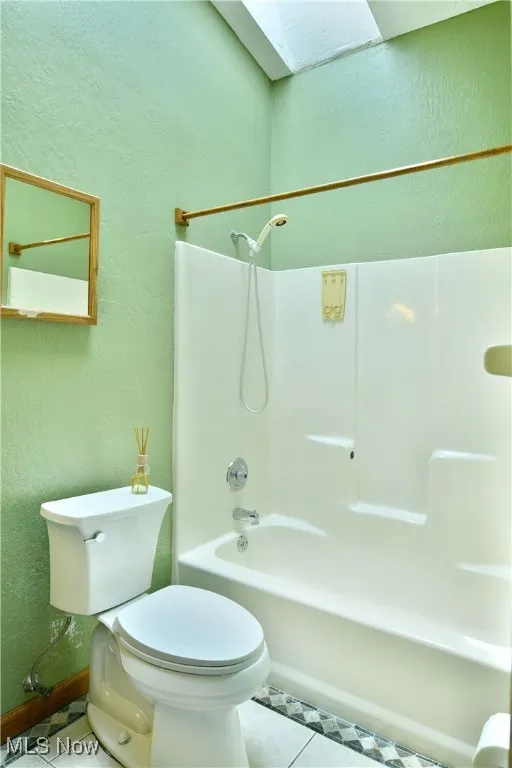 Bathroom with tub / shower combination, tile patterned flooring, and a textured wall