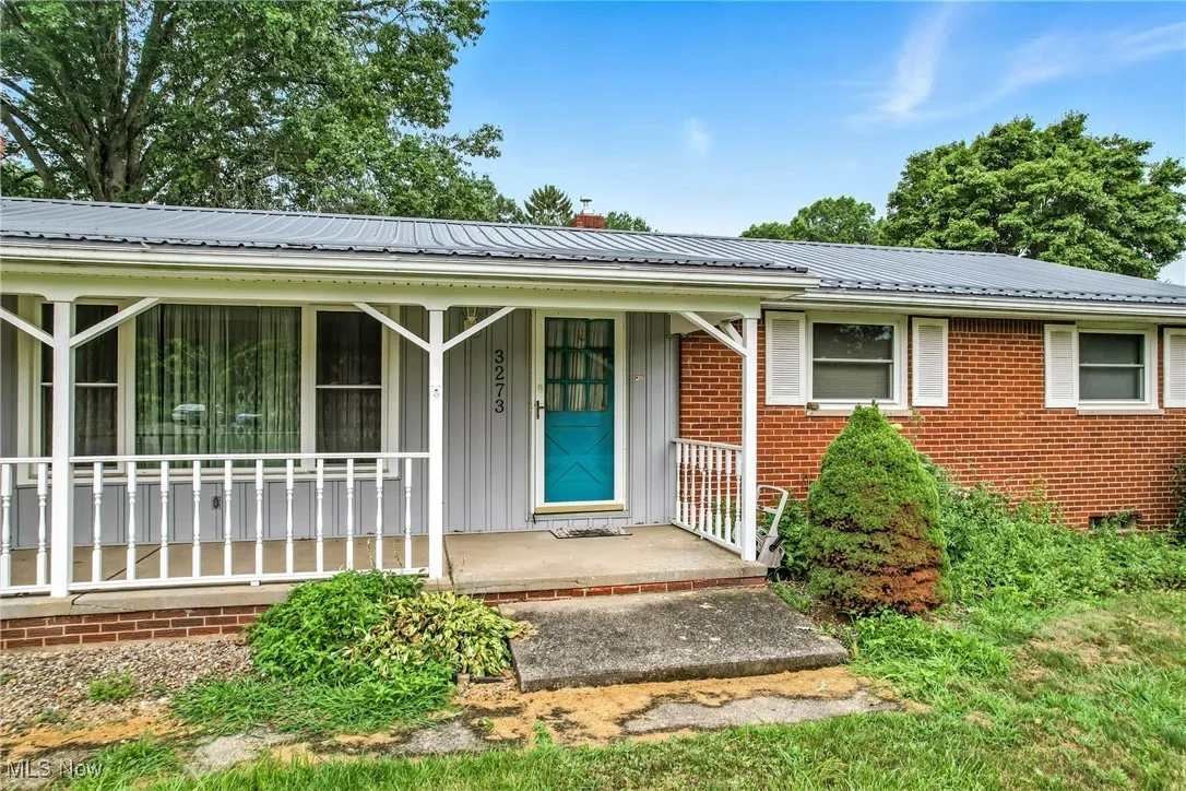 View of front of property featuring brick siding, a metal roof, and board and batten siding