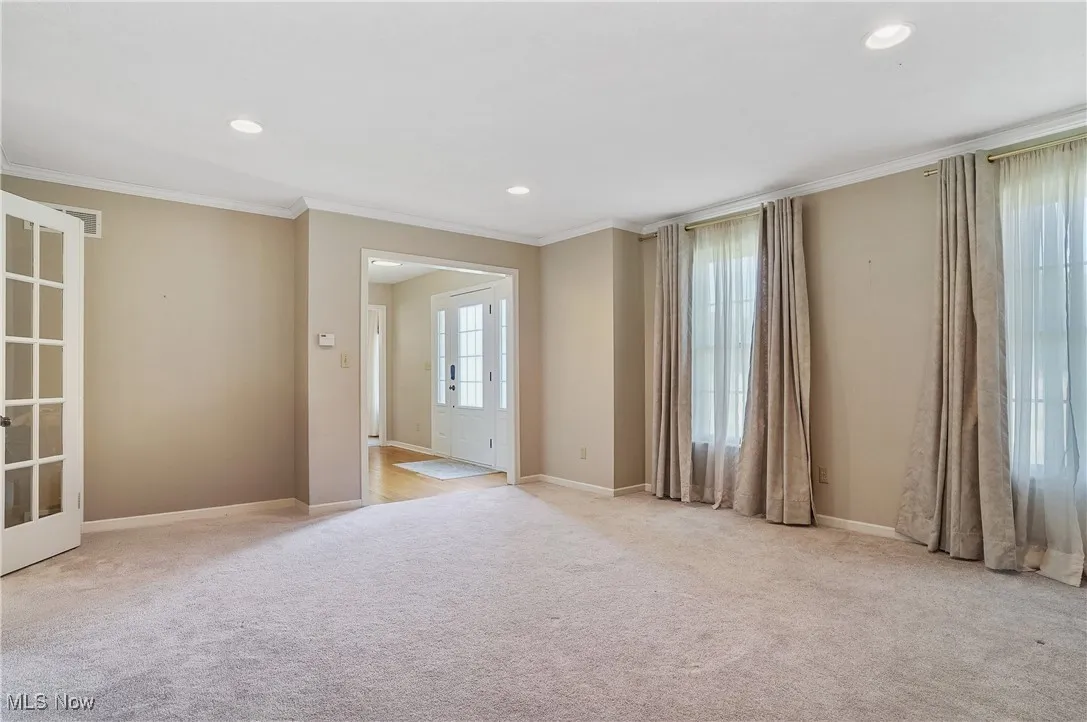 living room with light colored carpet, crown molding, and recessed lighting