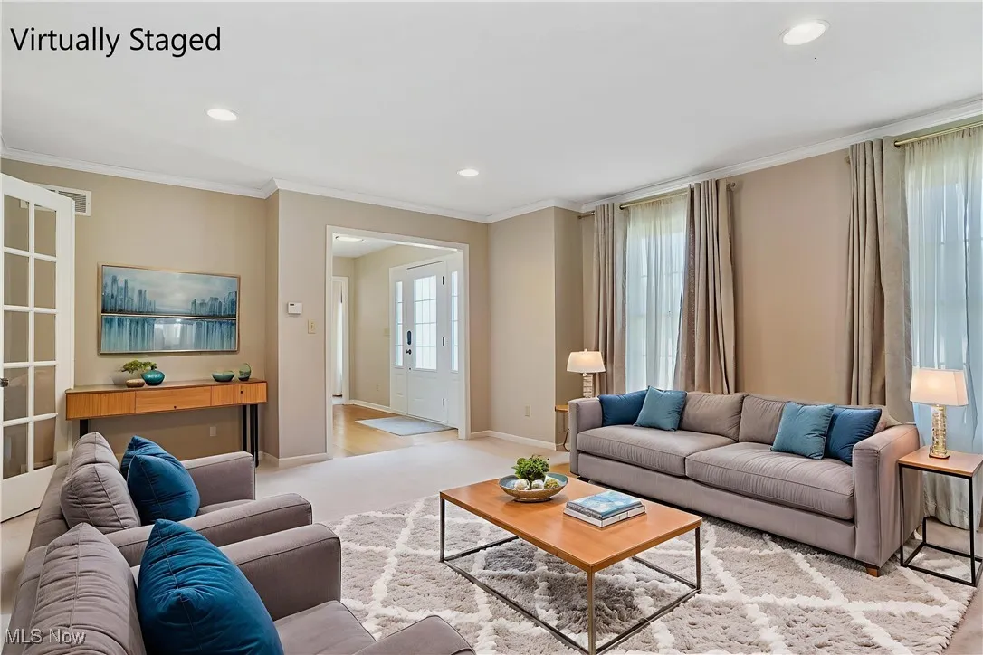 Living room featuring recessed lighting, ornamental molding, and light carpet