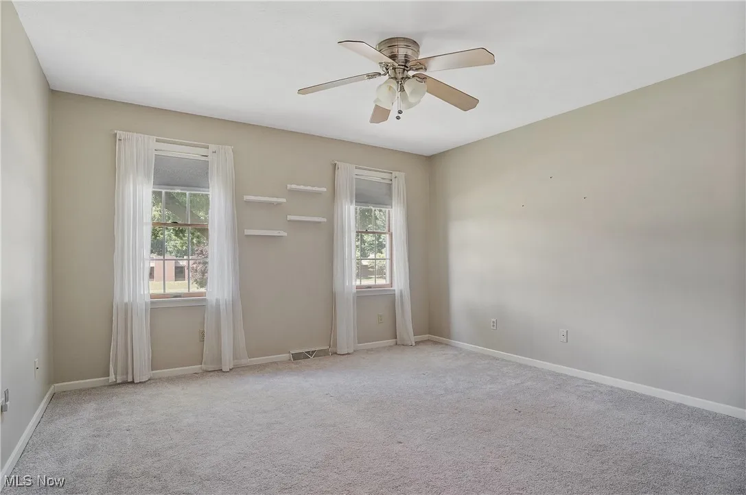 Spare room with healthy amount of natural light, carpet floors, and ceiling fan
