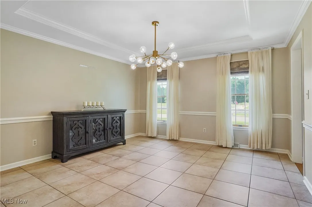 Unfurnished room featuring a chandelier, crown molding, and light tile patterned flooring