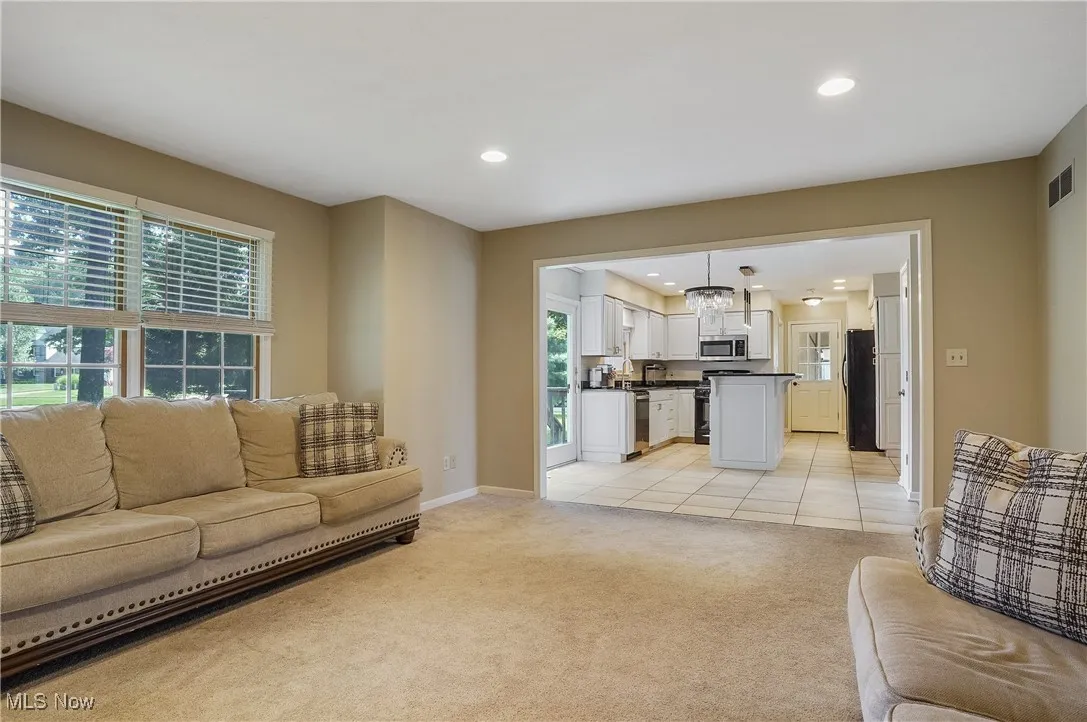 Living area with healthy amount of natural light, light carpet, recessed lighting, and light tile patterned floors