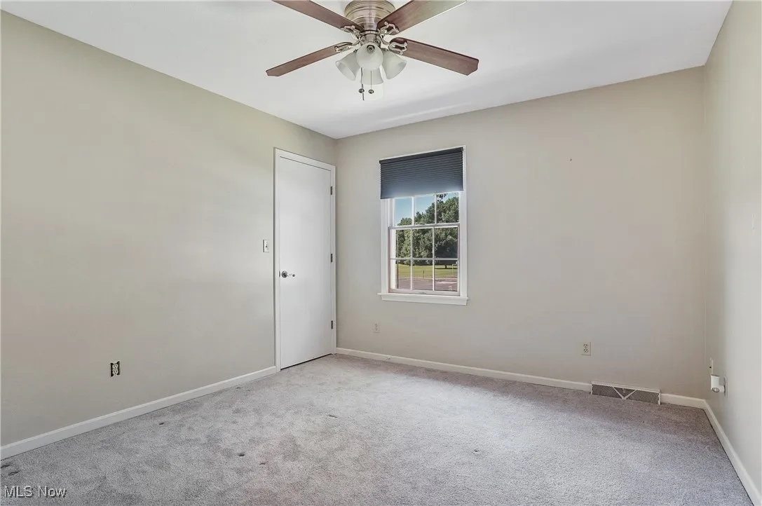 Unfurnished room with light carpet and a ceiling fan