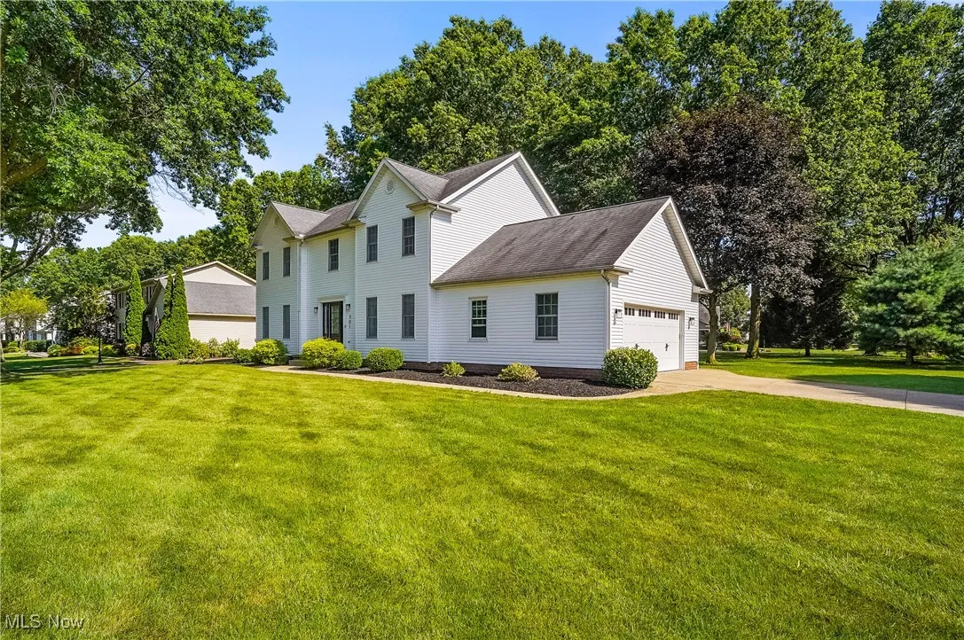Colonial house featuring concrete driveway, a front lawn, roof with shingles, and a garage