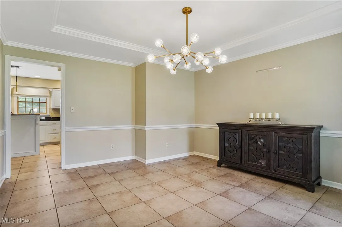 dining room featuring light tile patterned floors, a chandelier, and crown molding
