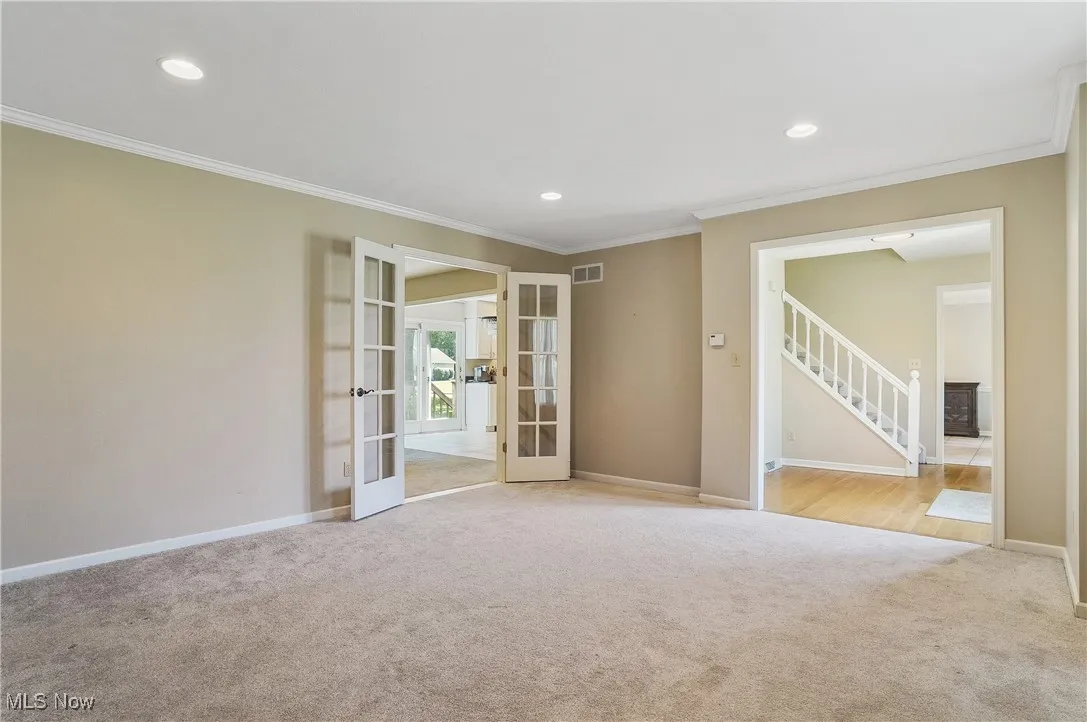 Unfurnished room with french doors, crown molding, carpet flooring, recessed lighting, and stairs