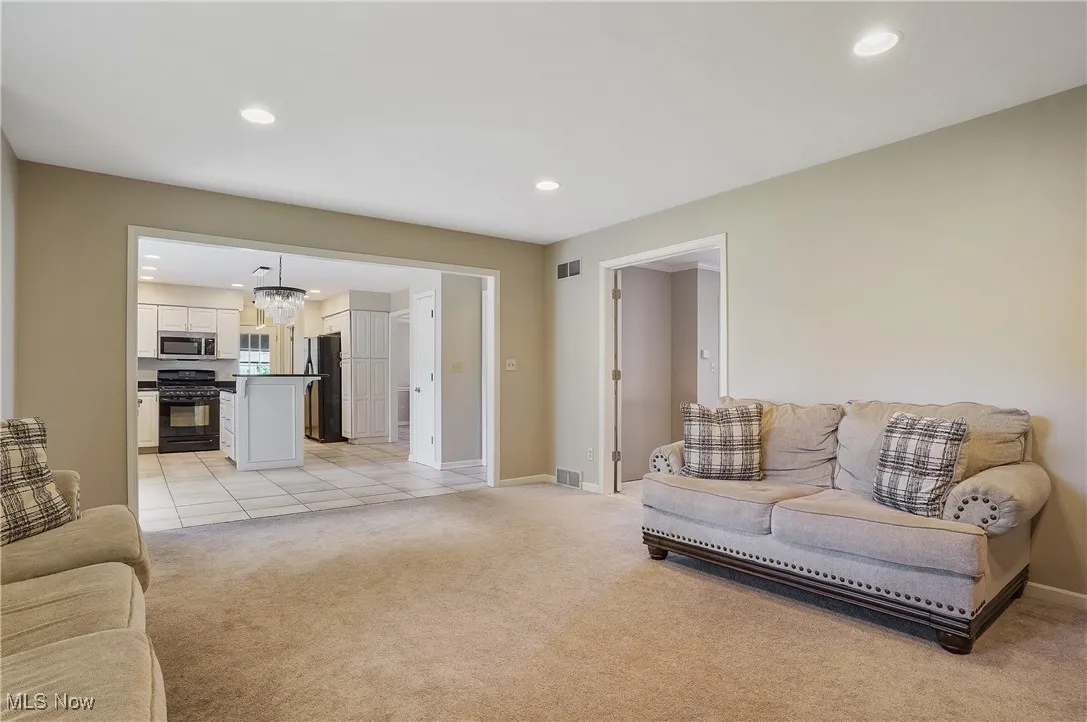 Living area featuring light carpet, recessed lighting, and a chandelier
