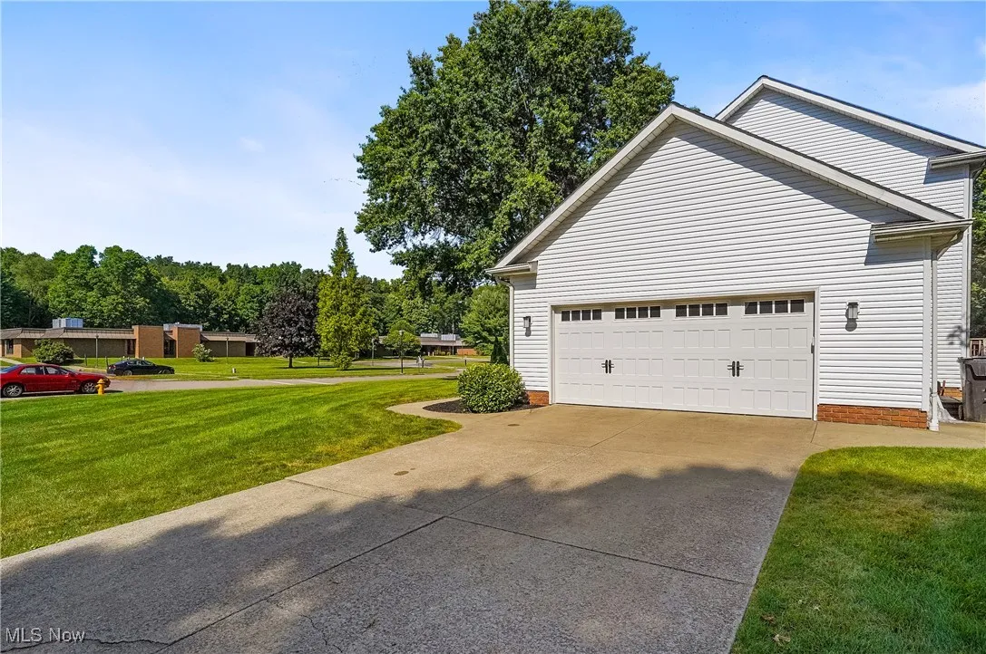 View of side of property featuring a lawn and concrete driveway
