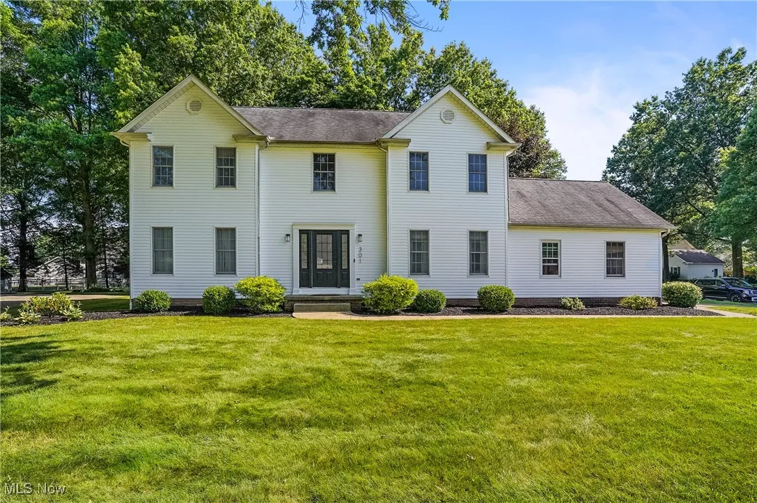 Colonial home featuring a front lawn and a shingled roof